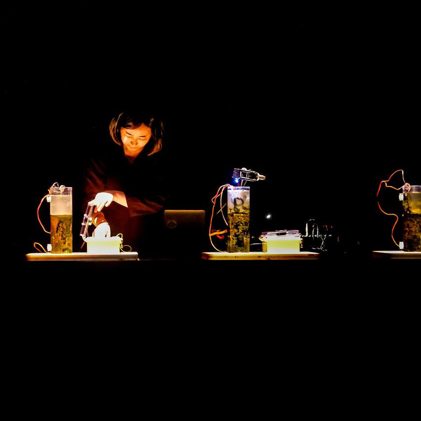 A woman wearing headphones, manipulating what looks like cylinders of liquid with wire attached.