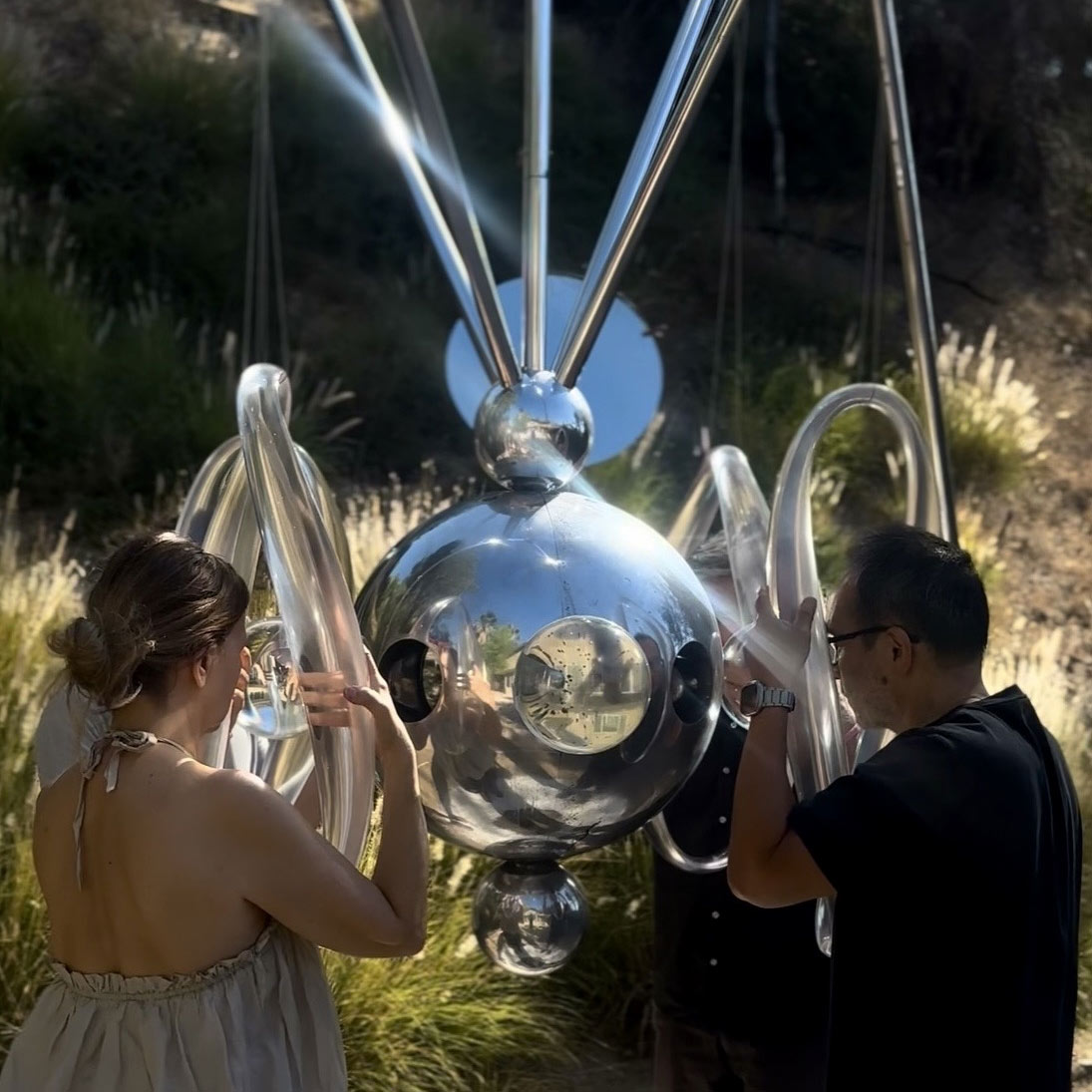 A man and woman peering into the metallic abstract sculpture.